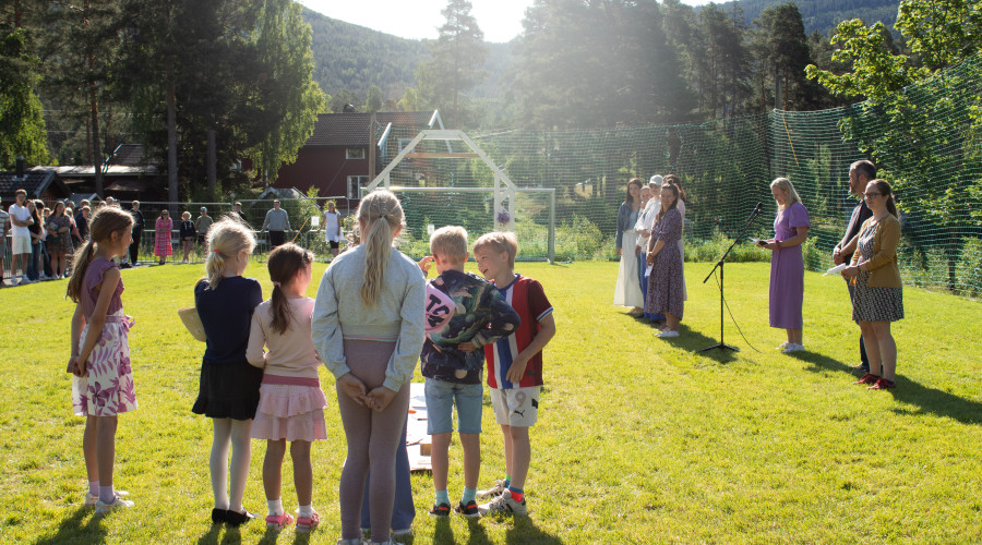 Elever står samlet på plen, venter på å bli lest opp